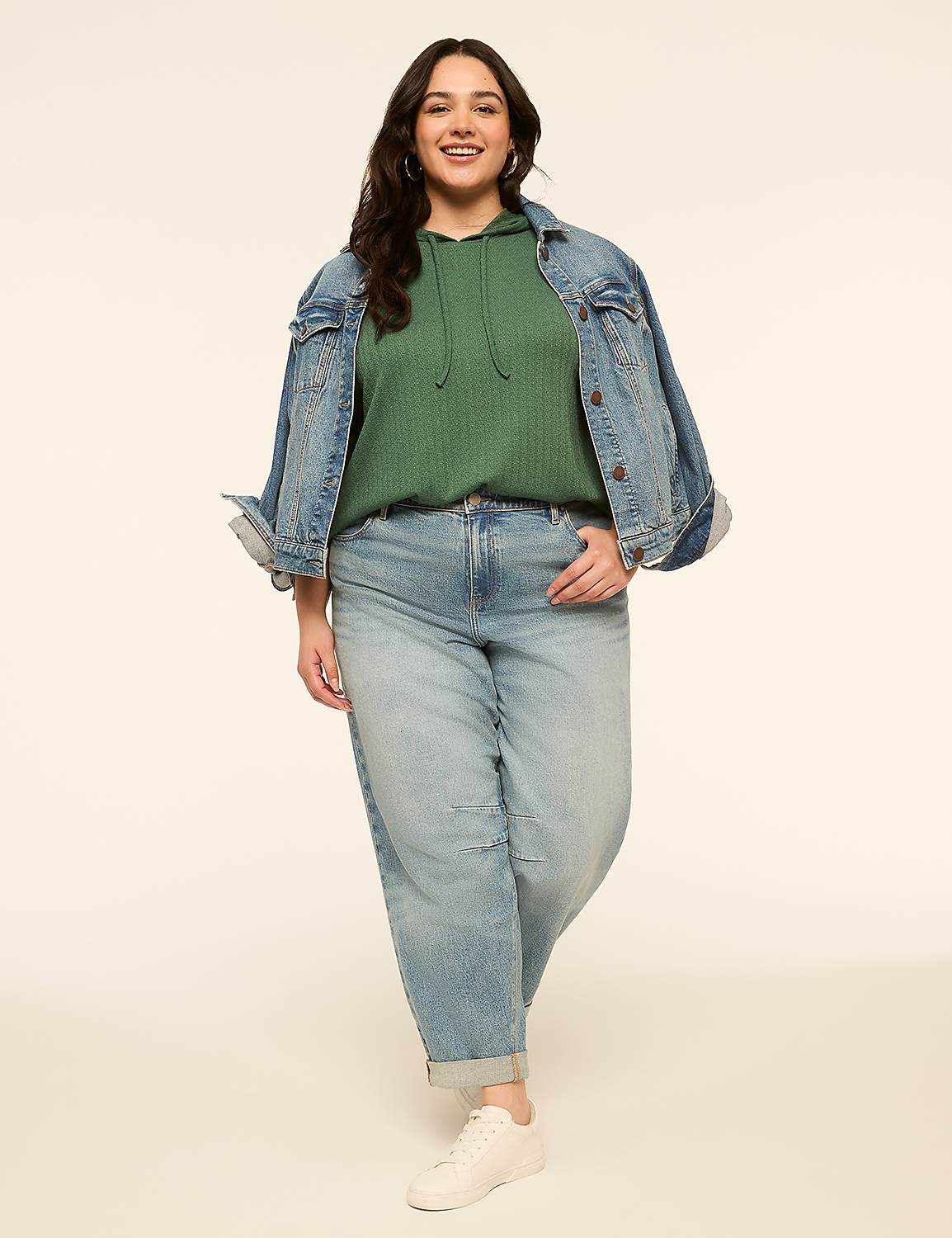 A smiling woman in a green hoodie, denim jacket, and light wash jeans stands against a plain, light-colored background. Product Image 3