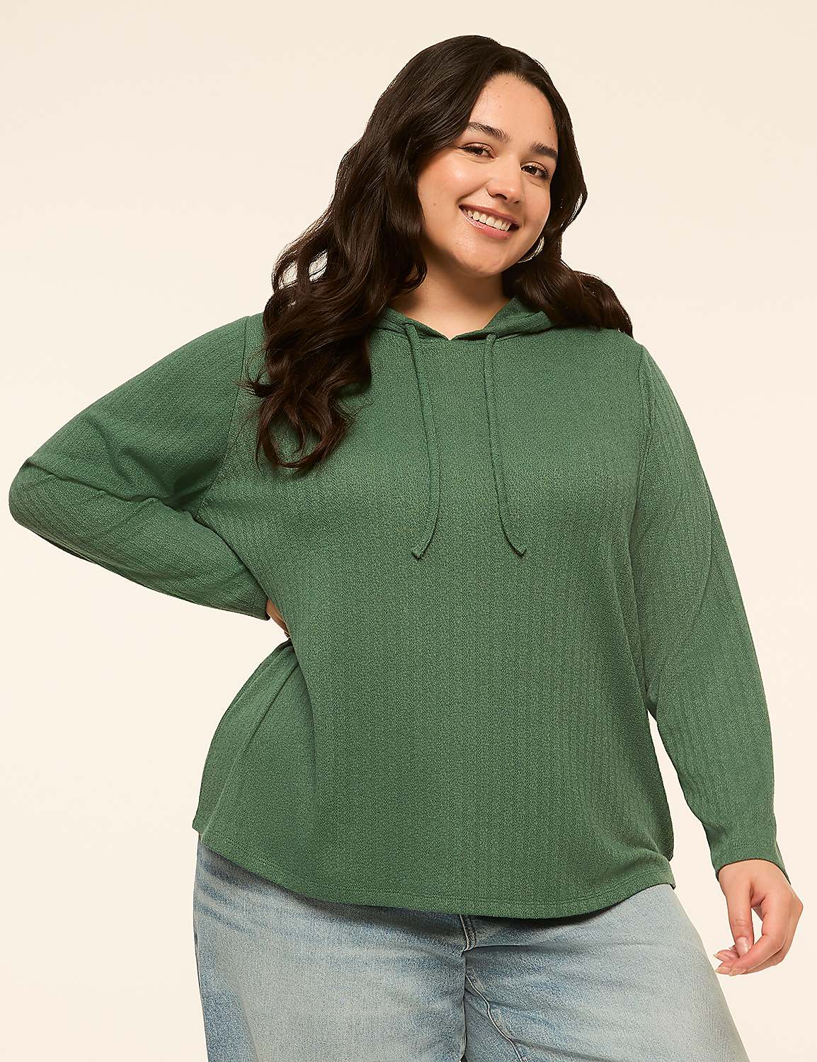 A smiling woman in a green hooded sweatshirt and jeans stands against a plain, light-colored background. Product Image 1
