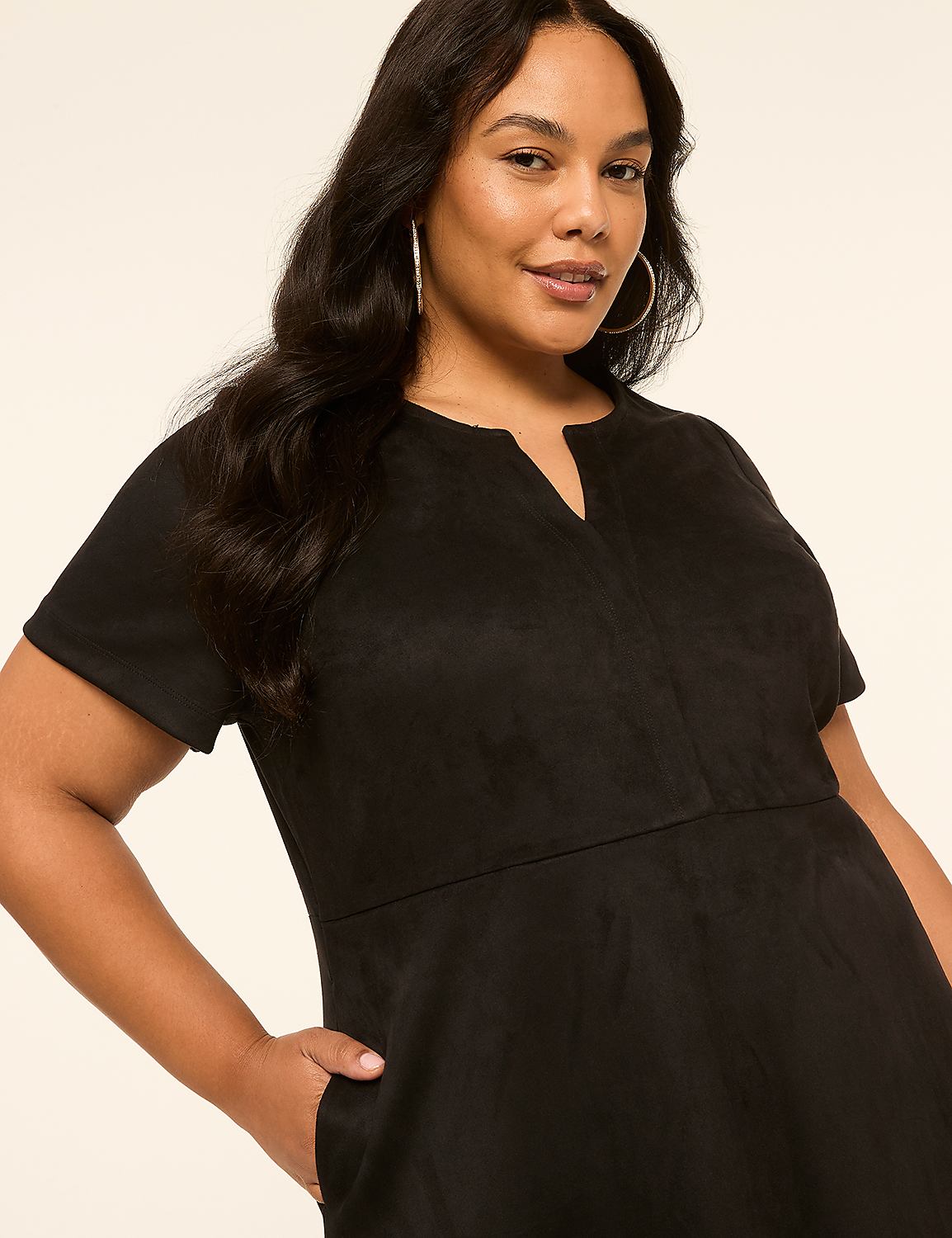 A woman in a black dress with her hand in her pocket stands against a plain, light-colored background. Product Image 3