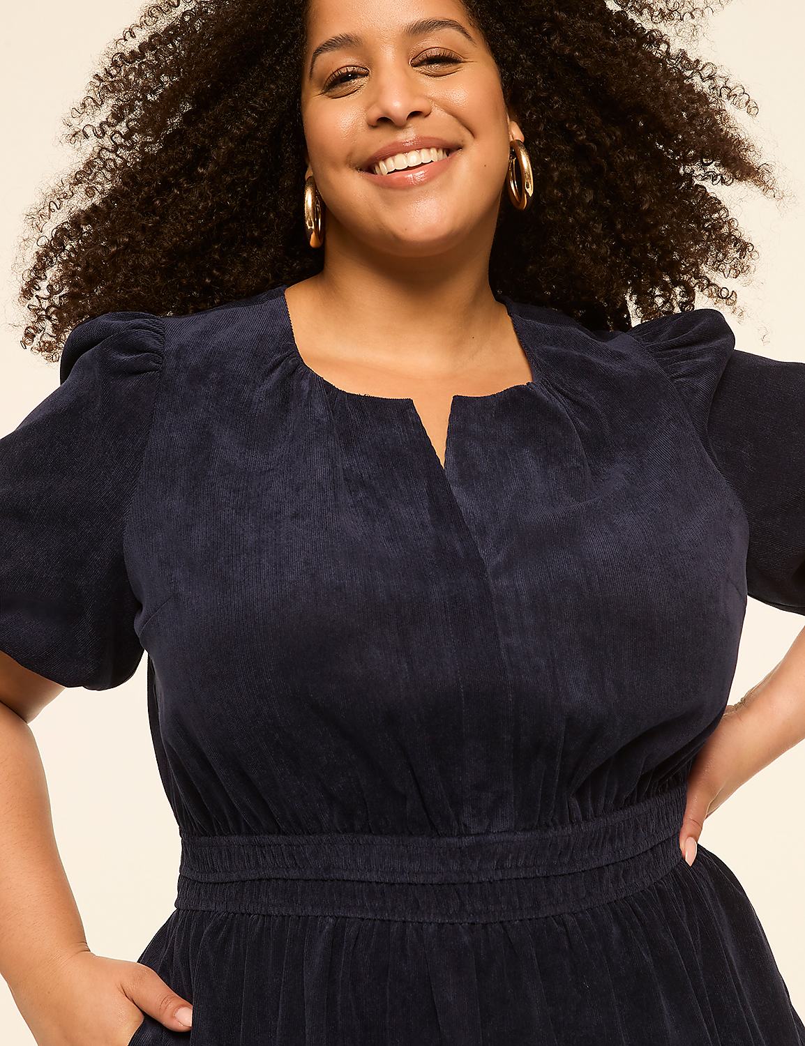 A smiling woman with curly hair in the foreground wears a navy corduroy dress against a plain, light-colored background. Product Image 3