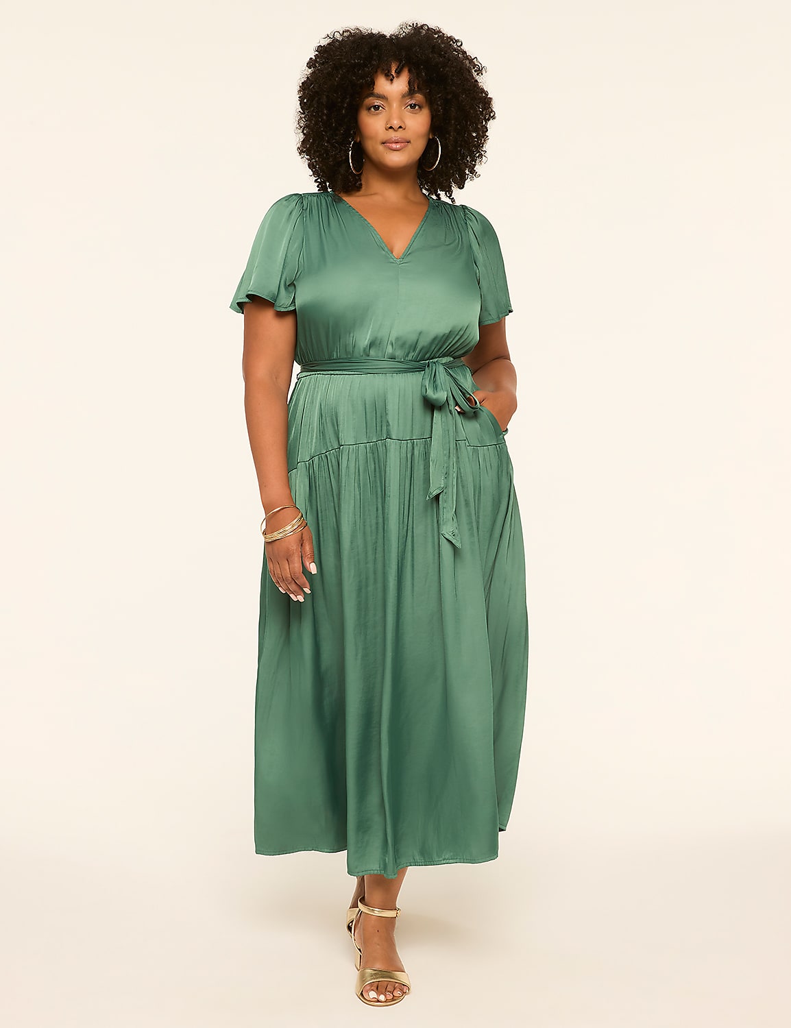 A woman in a green satin dress stands against a plain, light-colored background. Product Image 1