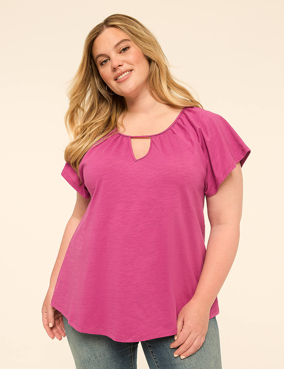 A woman in a fuchsia top and jeans smiles against a plain, light background. Product Image 1