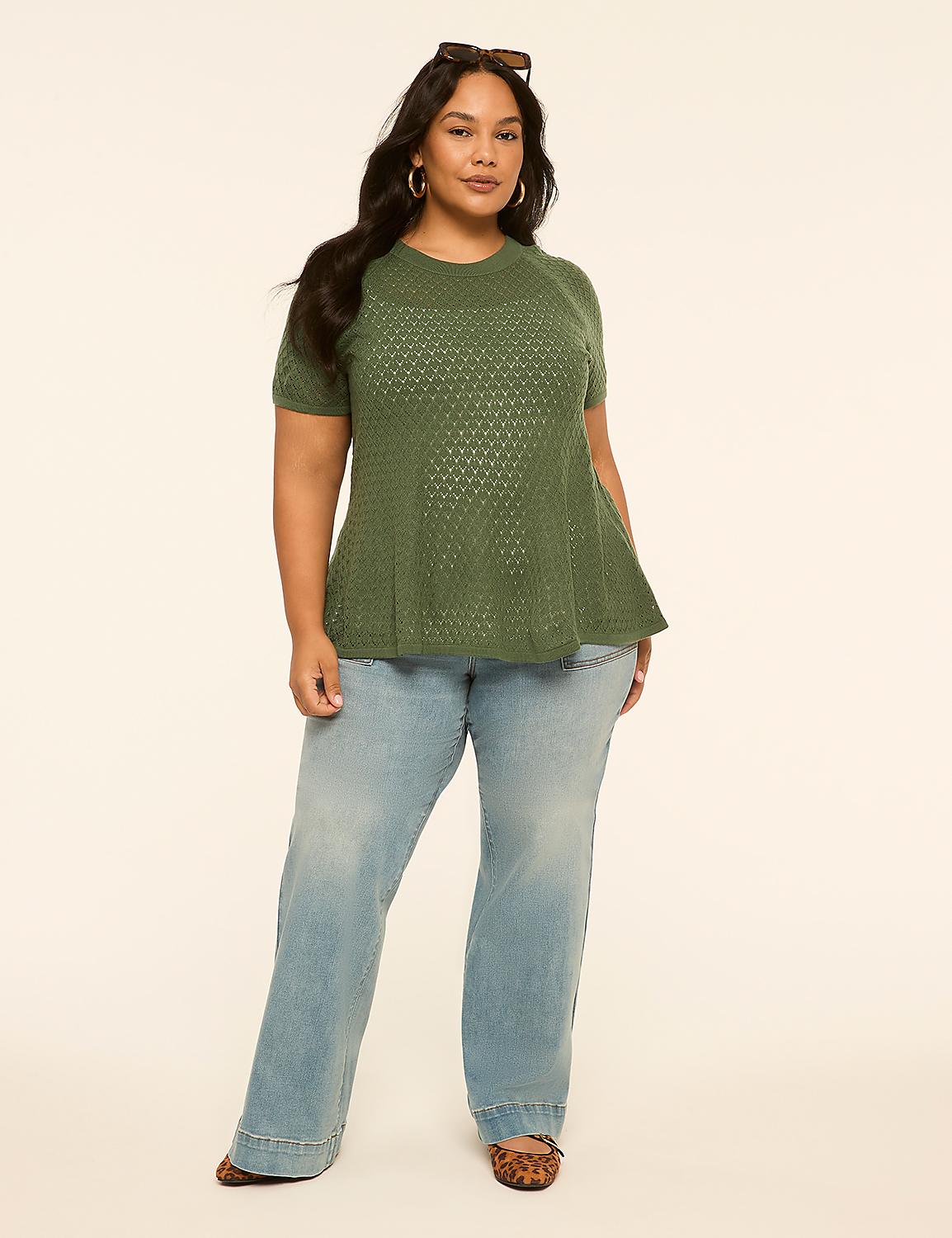 A woman in a green sweater and light wash jeans stands against a plain, light-colored background. Product Image 3