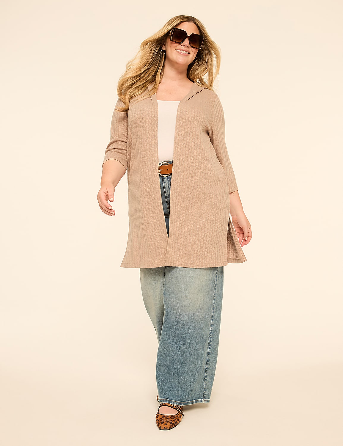 A woman in a beige cardigan and wide-leg jeans walks forward against a plain, light-colored background. Product Image 3