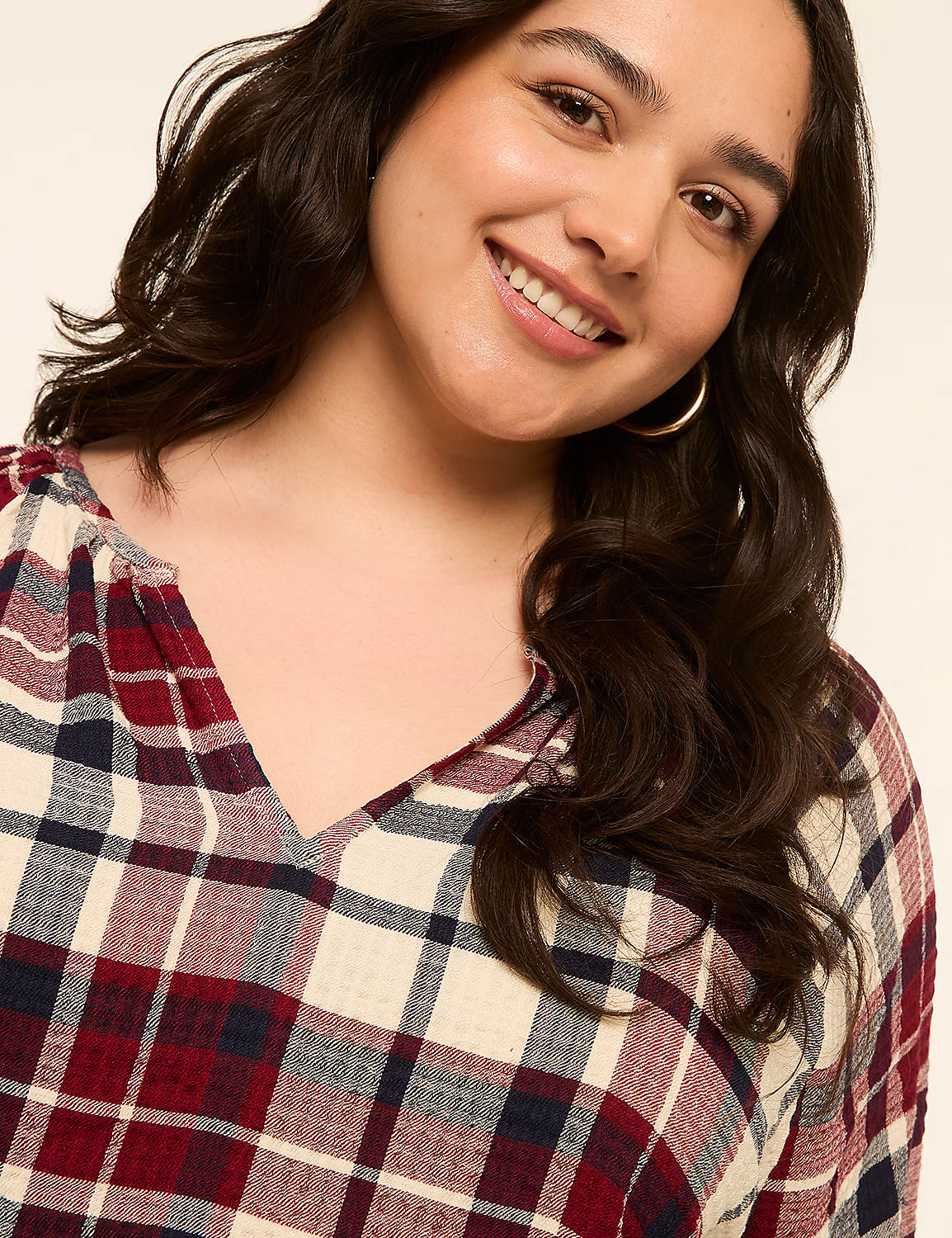 A smiling woman with dark hair wears a plaid shirt in the foreground against a plain, light-colored background. Product Image 4