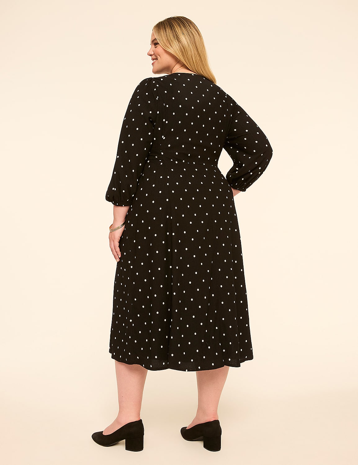A woman in a black polka dot dress stands against a plain, light-colored background. Product Image 2