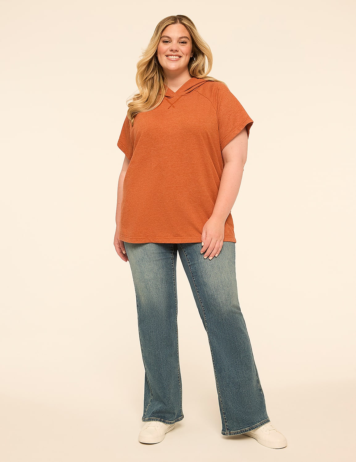A smiling woman in a rust-colored hoodie and blue jeans stands against a plain, light-colored background. Product Image 3