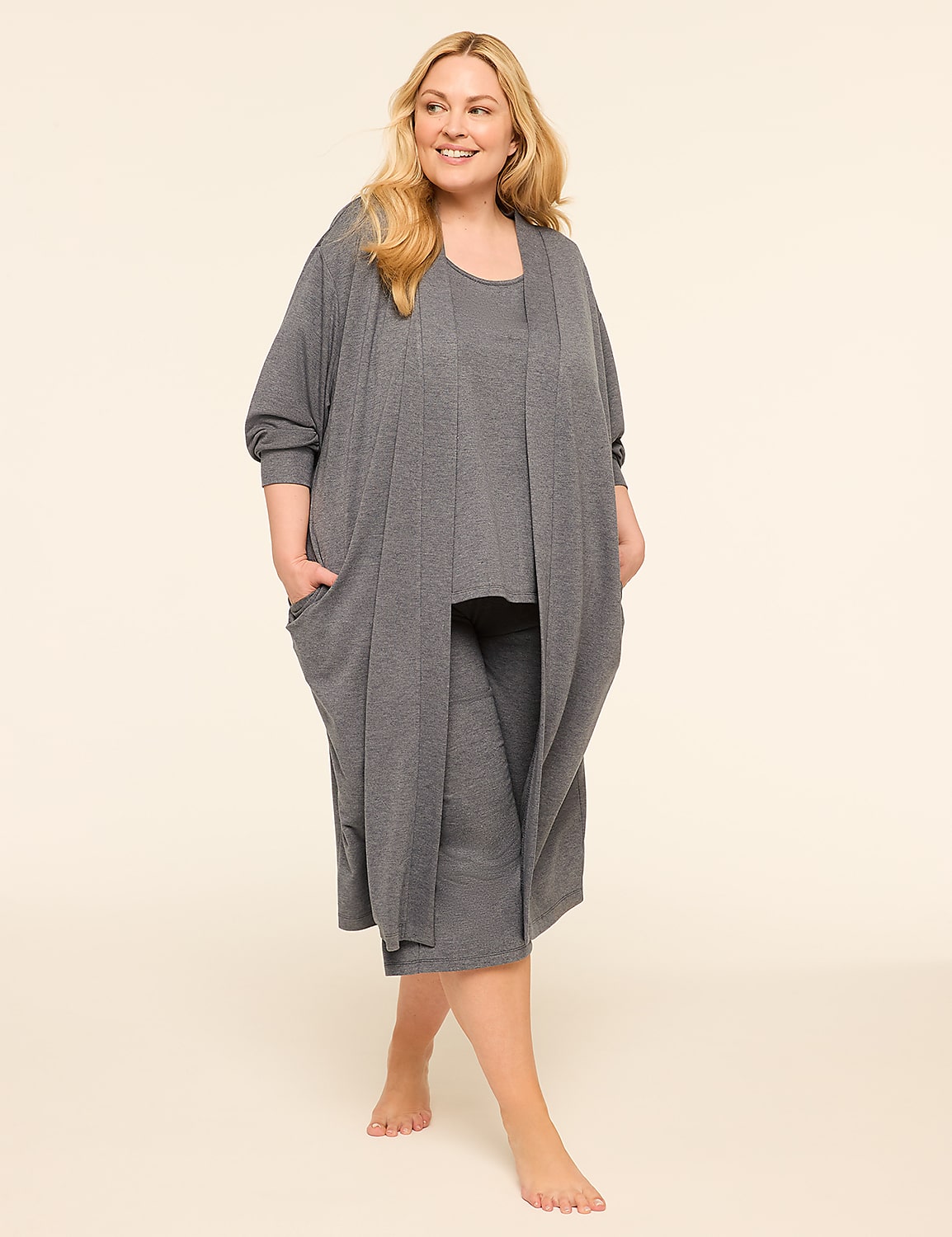 A smiling woman in a grey loungewear set stands barefoot against a plain, light background. Product Image 3
