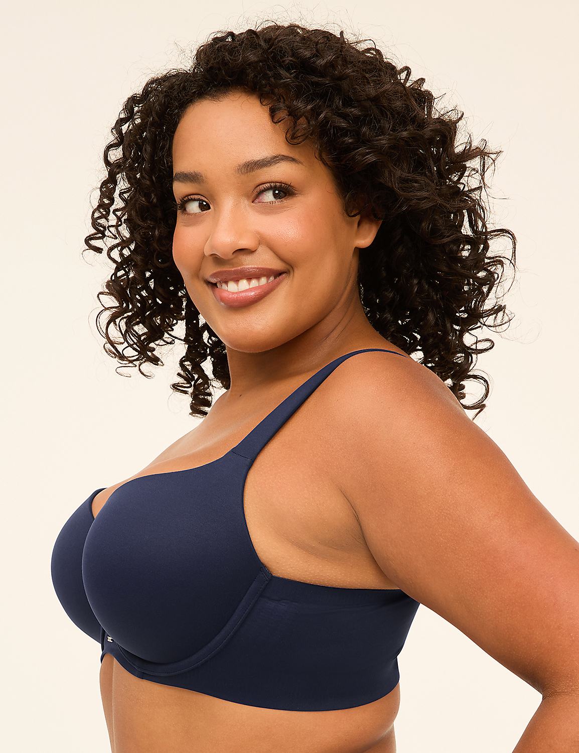 A smiling woman with curly dark hair wears a navy blue bra against a plain, light background. Product Image 4