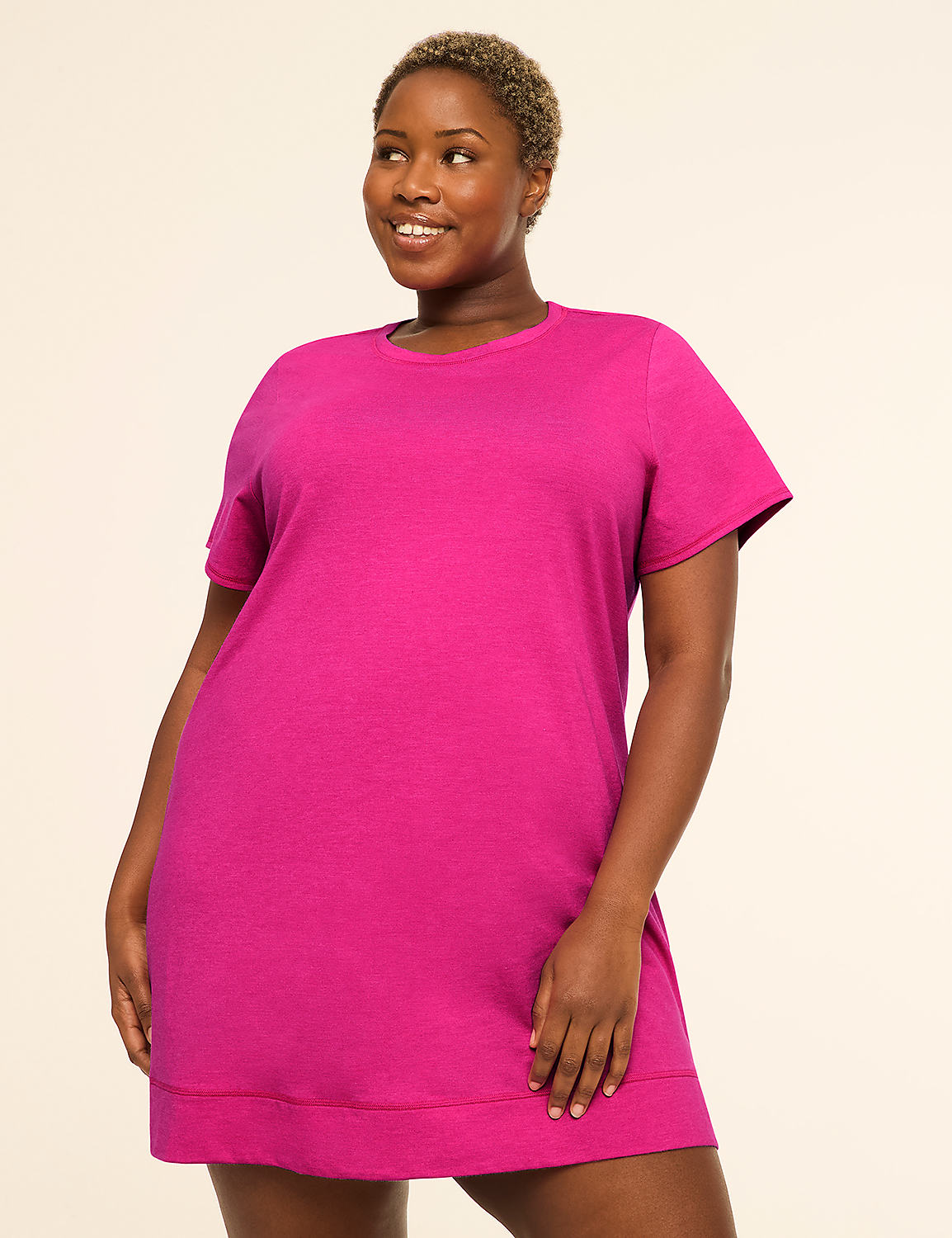 A smiling woman in a bright pink t-shirt dress stands against a plain, light-colored background. Product Image 1