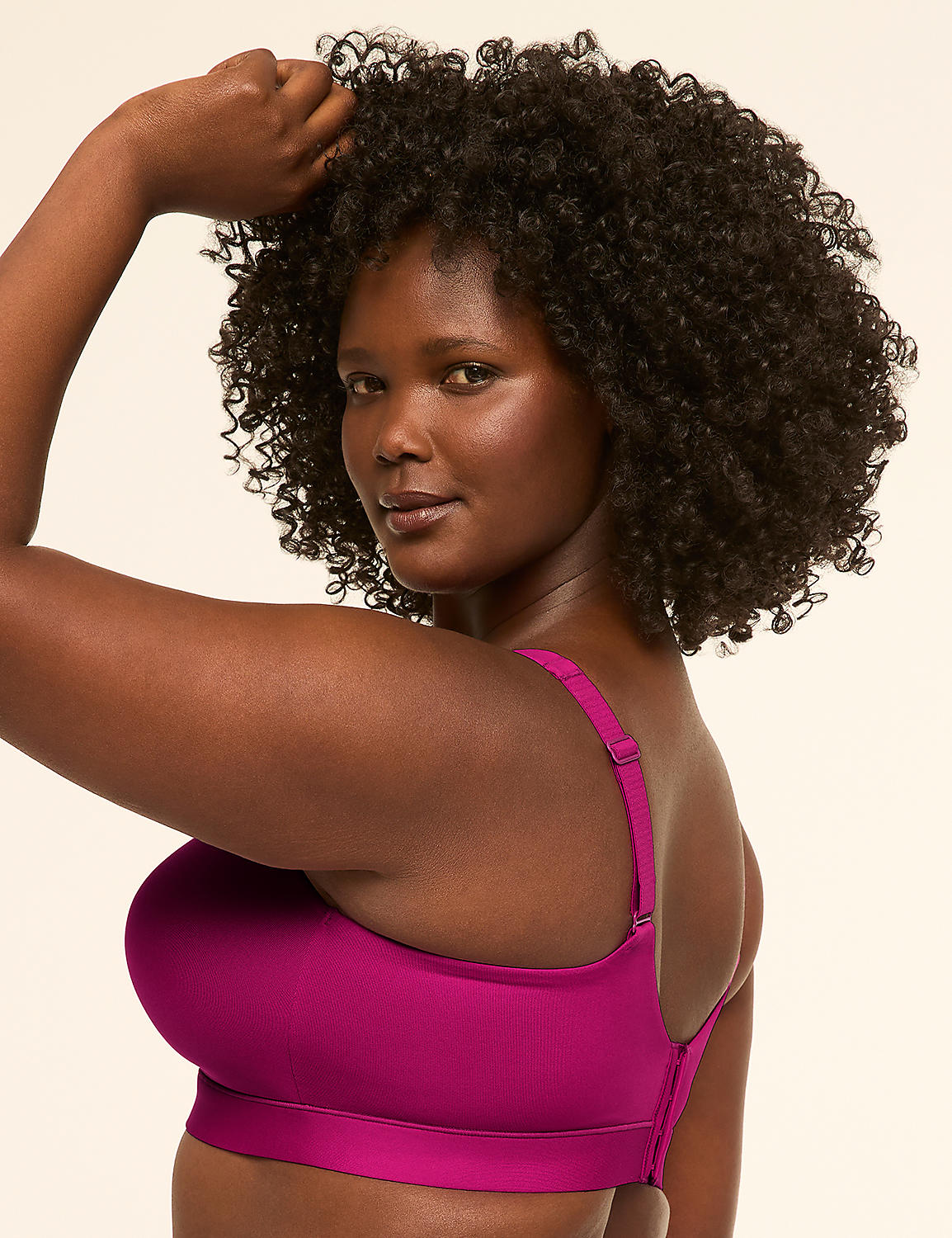 A woman with dark, curly hair poses in a magenta sports bra against a plain, light-colored background. Product Image 3