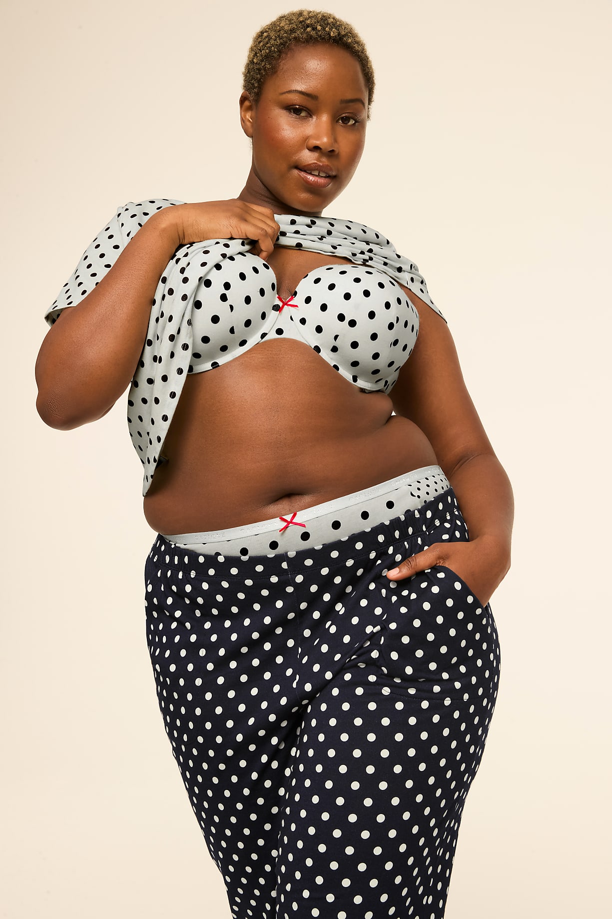 A woman in polka dot pajamas stands against a plain, light-colored background. Product Image 6