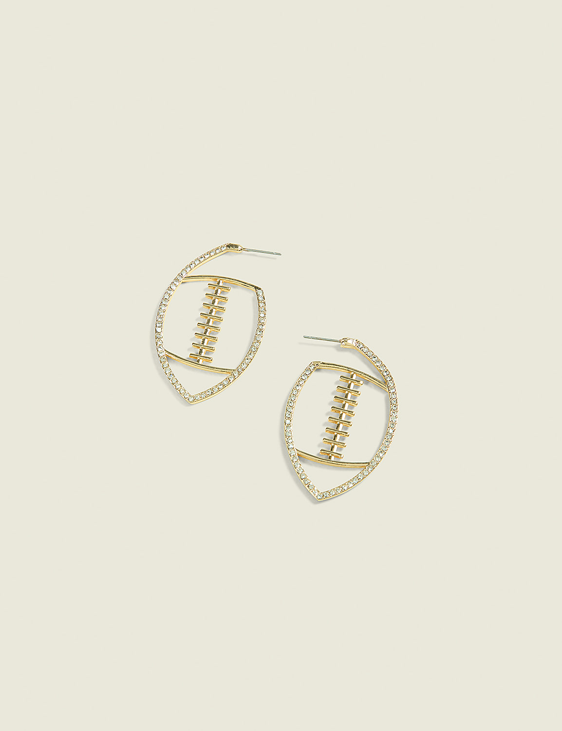 A pair of gold football-shaped earrings with diamond accents rests on a pale yellow background. Product Image 1