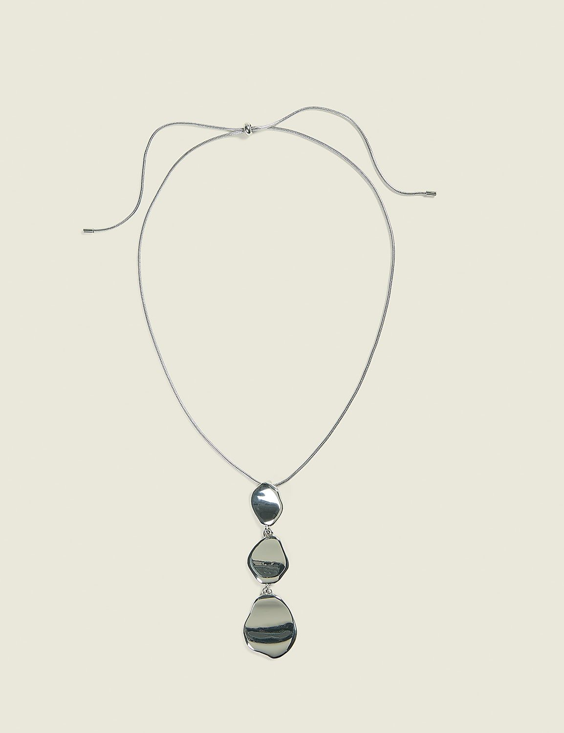 A silver pendant necklace with three irregular, polished stones hangs against a plain, light beige background. Product Image 1