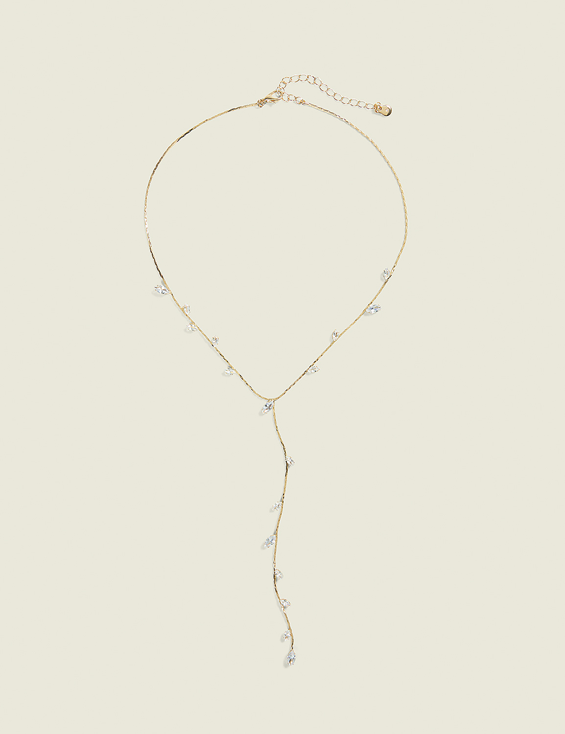 A delicate gold necklace with scattered clear crystals hangs against a plain, light beige background. Product Image 1