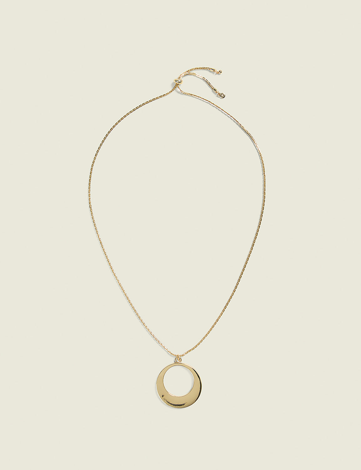 A gold oval pendant hangs from a delicate gold chain against a plain, light beige background. Product Image 1
