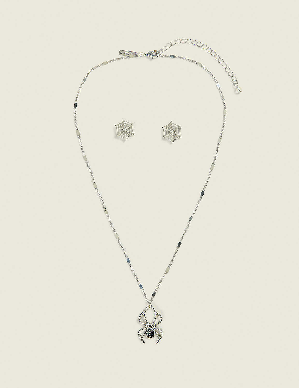 A silver spider necklace and matching spiderweb earrings rest on a plain, light-colored background. Product Image 1