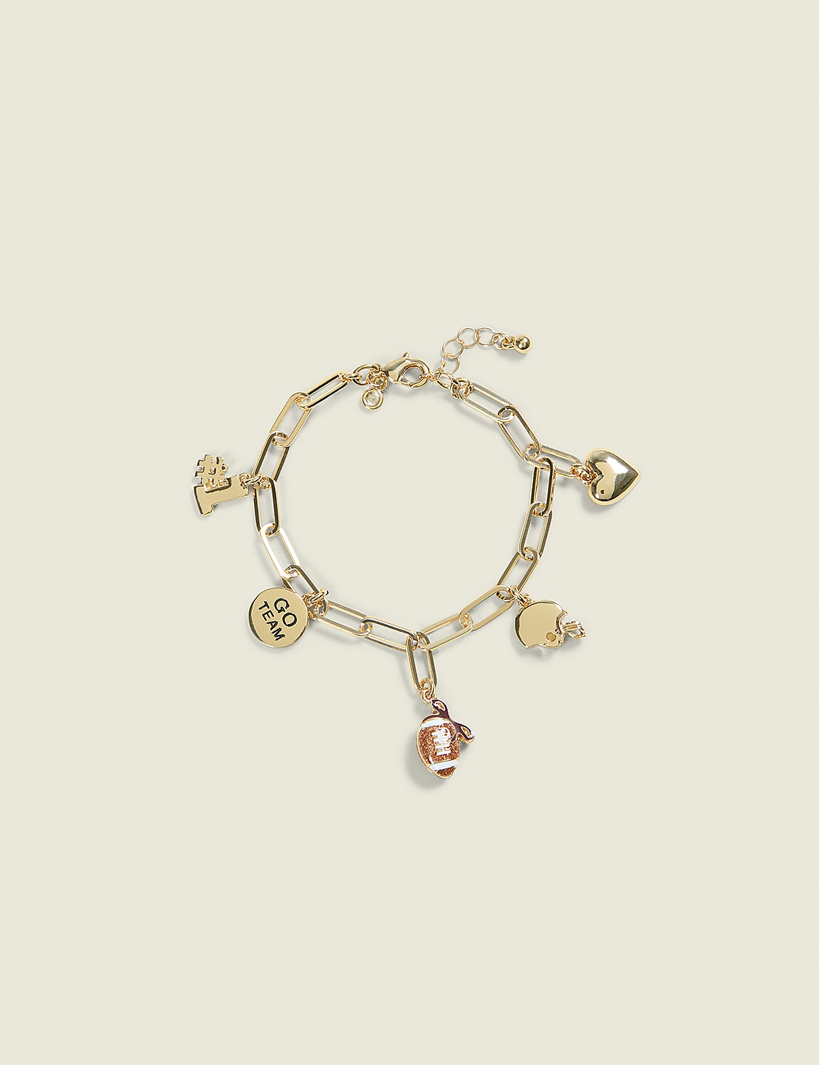 A gold charm bracelet with football, heart, and team-themed charms rests on a pale yellow background. Product Image 1