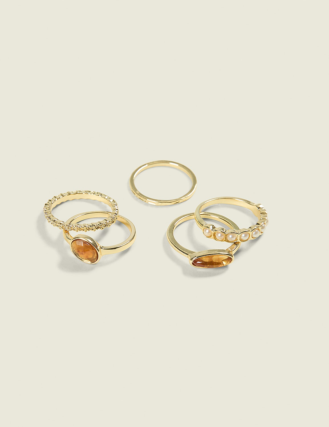 Several gold rings, some adorned with stones and pearls, are arranged on a plain, light-colored background. Product Image 1