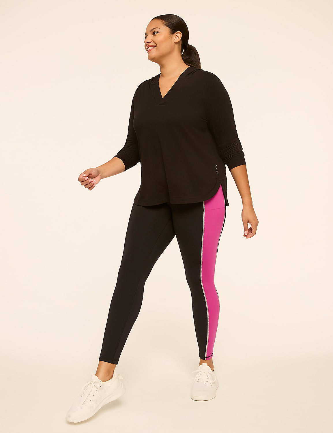 A woman in a black hoodie and black and pink leggings walks against a plain, light-colored background. Product Image 3