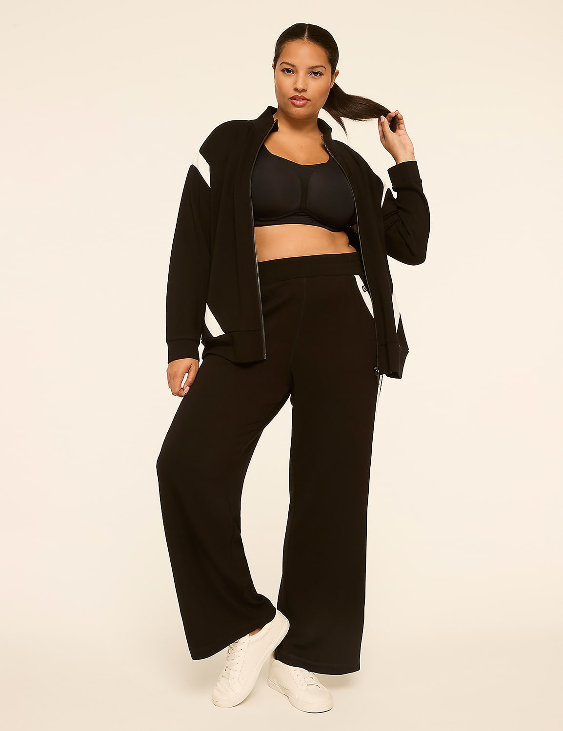 A woman in a black tracksuit stands against a plain, light-colored background. Product Image 3