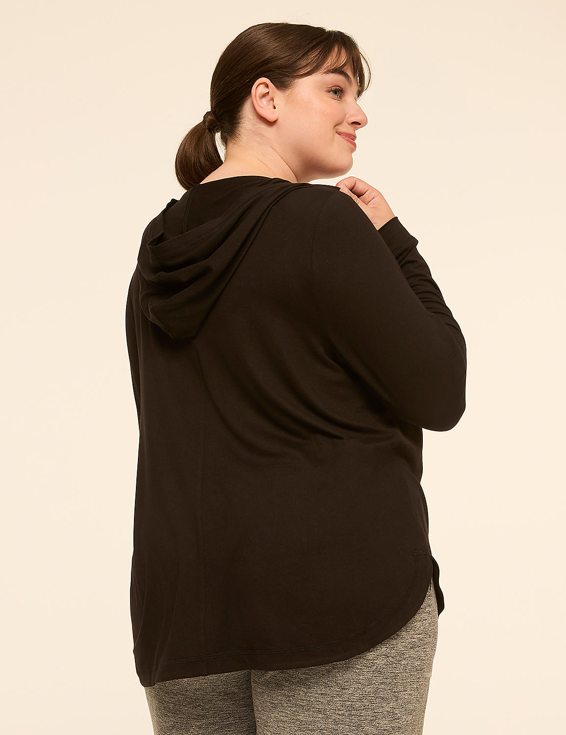 A woman in a black hoodie and grey leggings stands against a plain, light-colored background. Product Image 2