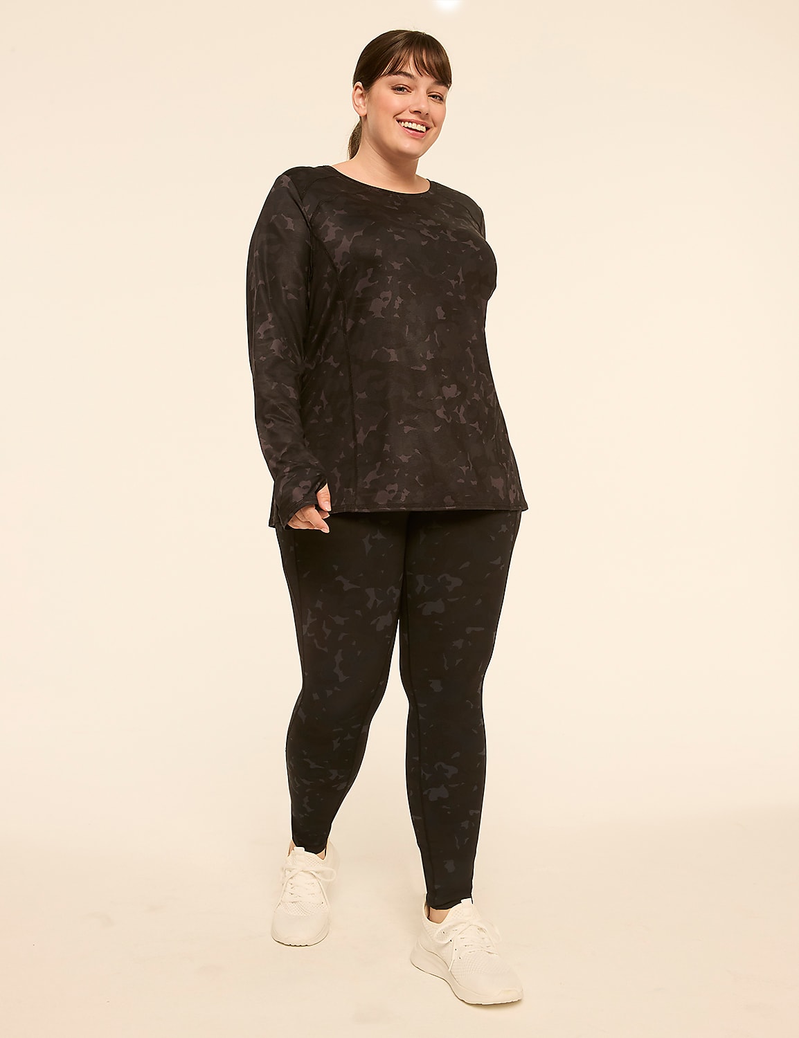 A smiling woman in a black patterned long-sleeved shirt and matching leggings stands against a plain, light-colored background. Product Image 3
