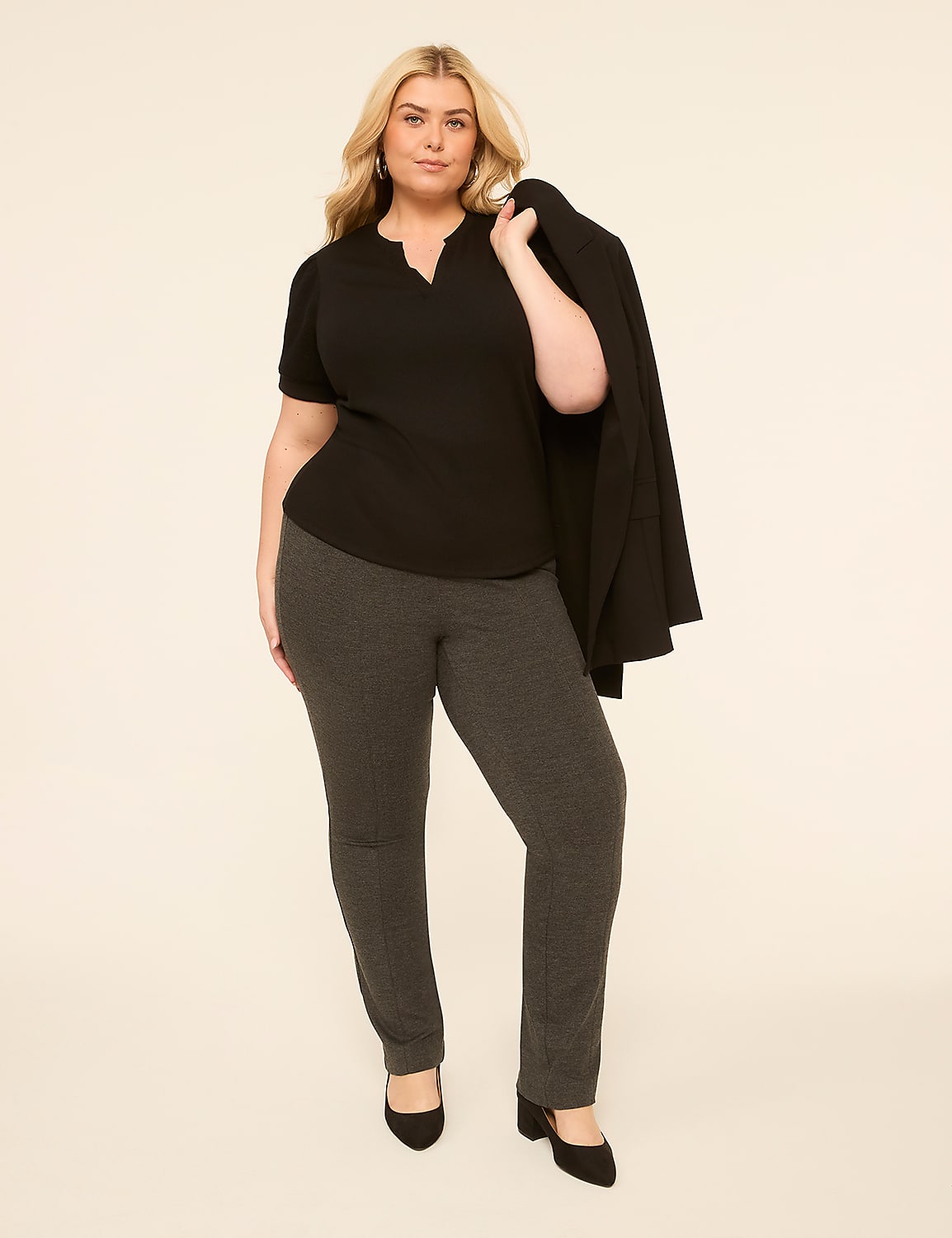 A woman in a black top and gray pants stands in front of a plain, light-colored background, with a black blazer draped over her shoulder. Product Image 3