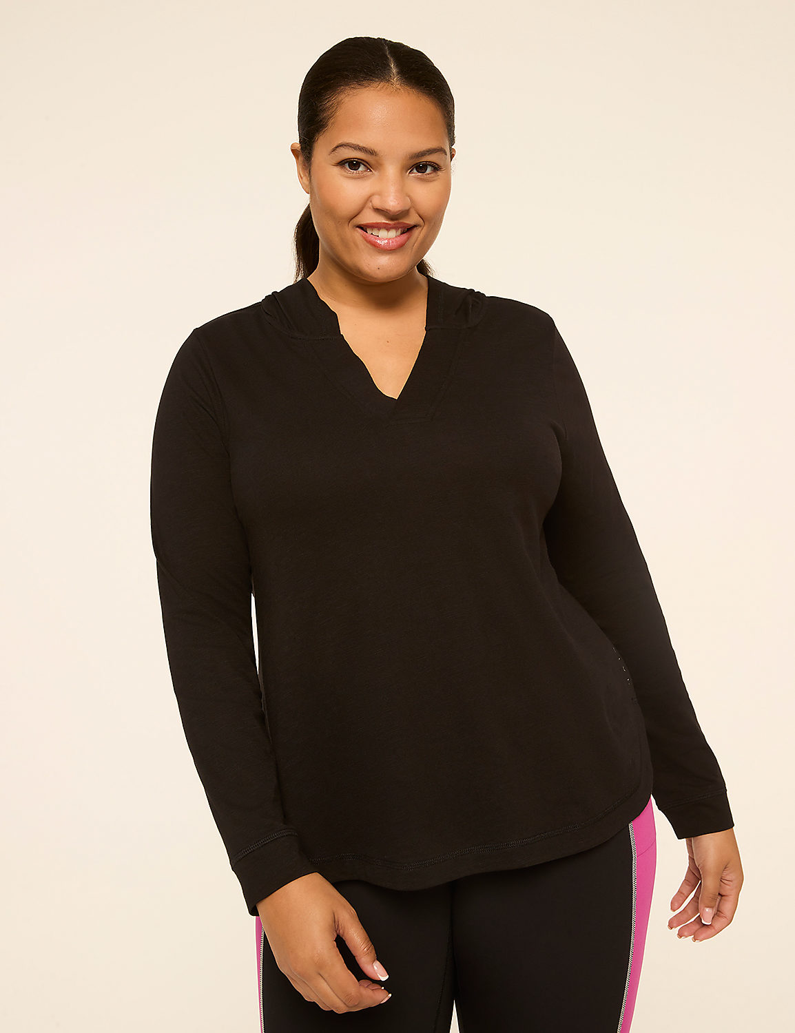 A smiling woman in a black hoodie and athletic leggings stands against a plain, light-colored background. Product Image 1