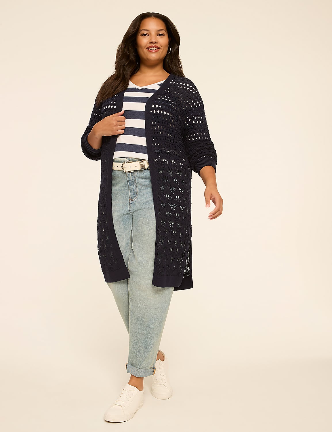 A woman in a striped shirt, jeans, and a long navy cardigan stands against a plain, light-colored background. Product Image 1