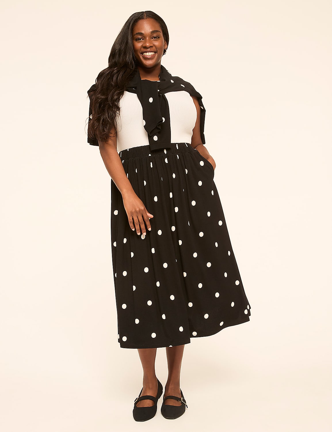 A smiling woman in a polka dot dress stands against a plain, light-colored background. Product Image 3