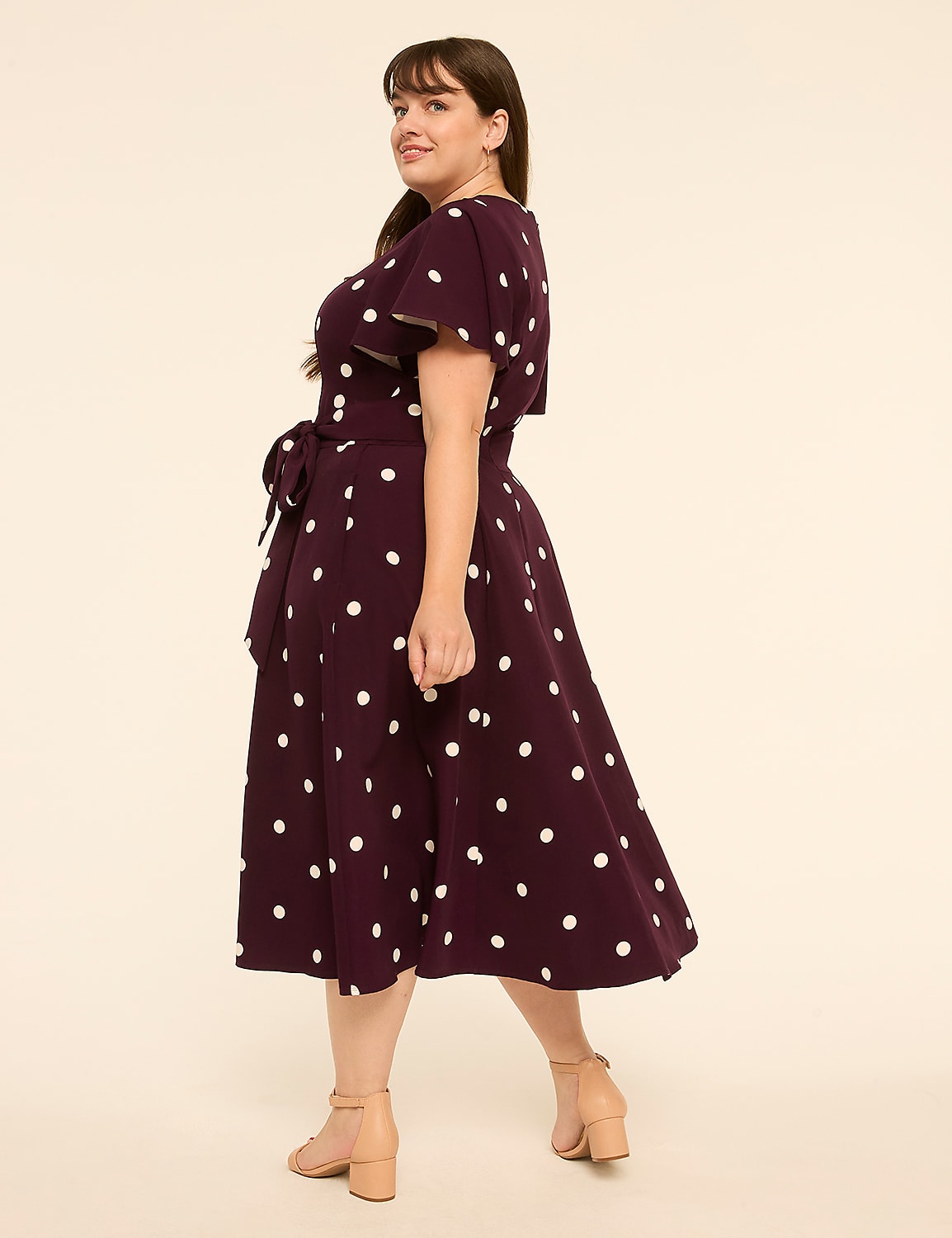 A woman in a polka dot dress stands against a plain, light-colored background. Product Image 2