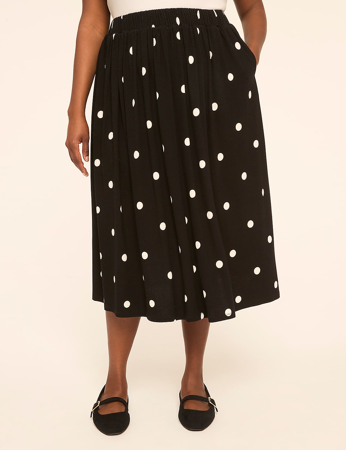 A person wearing a black polka dot skirt and black flats stands against a plain, light-colored background. Product Image 1