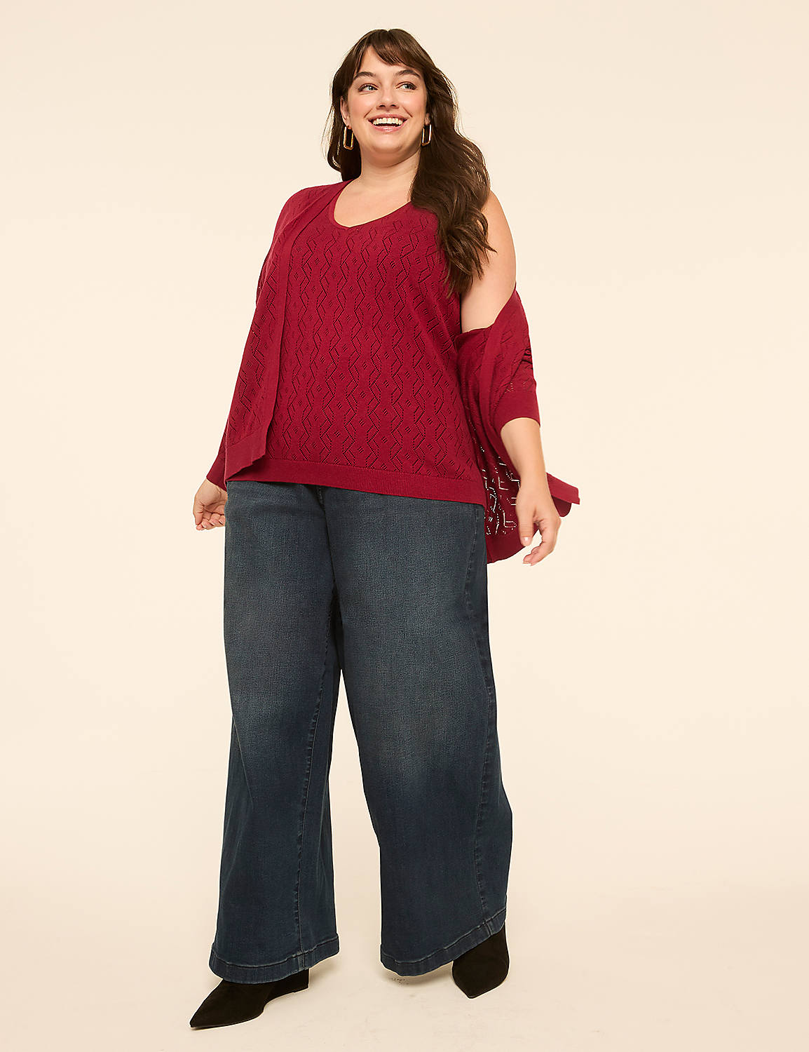 A smiling woman in a red top and wide-leg jeans stands against a plain, light-colored background. Product Image 3