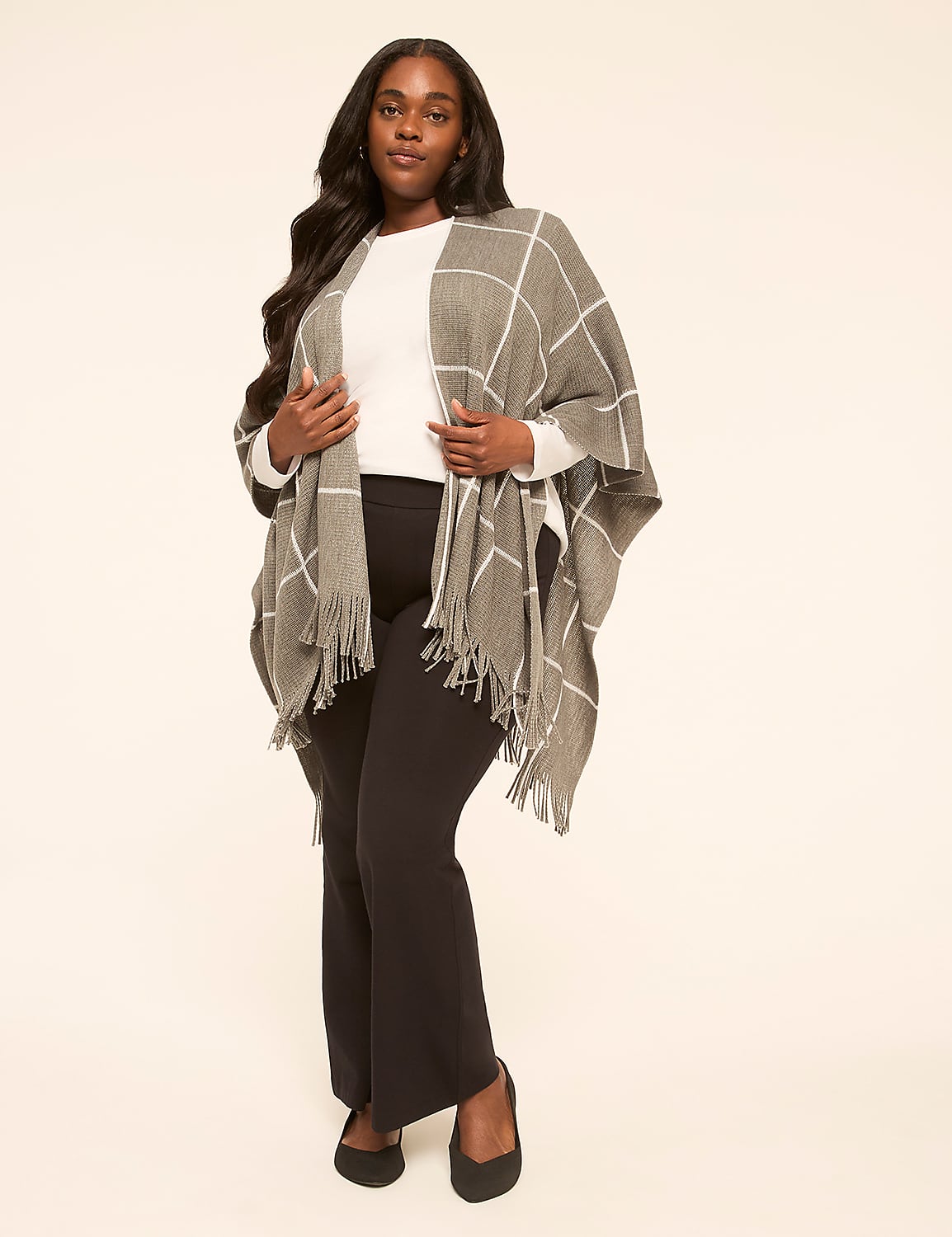 A woman in a plaid poncho and black pants stands against a plain, light-colored background. Product Image 3