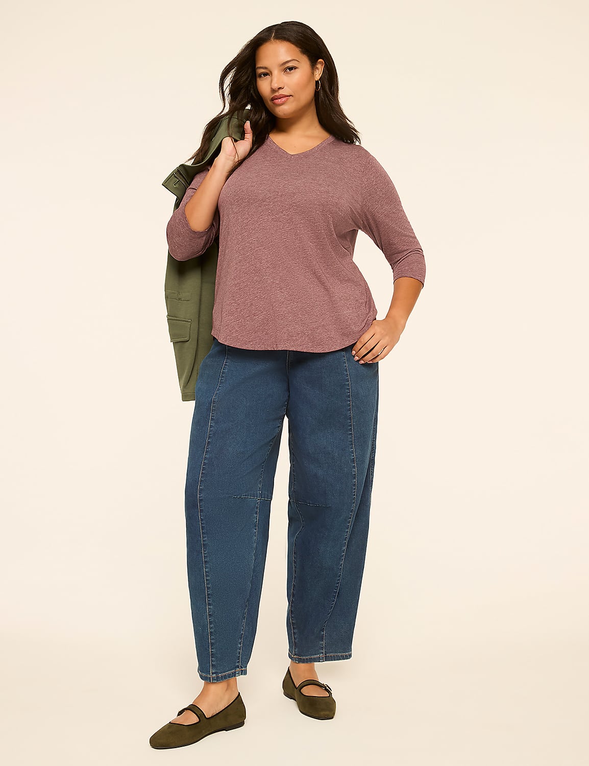 A woman in a mauve top and wide-leg jeans stands against a plain, light-colored background, with a green jacket draped over her shoulder. Product Image 3