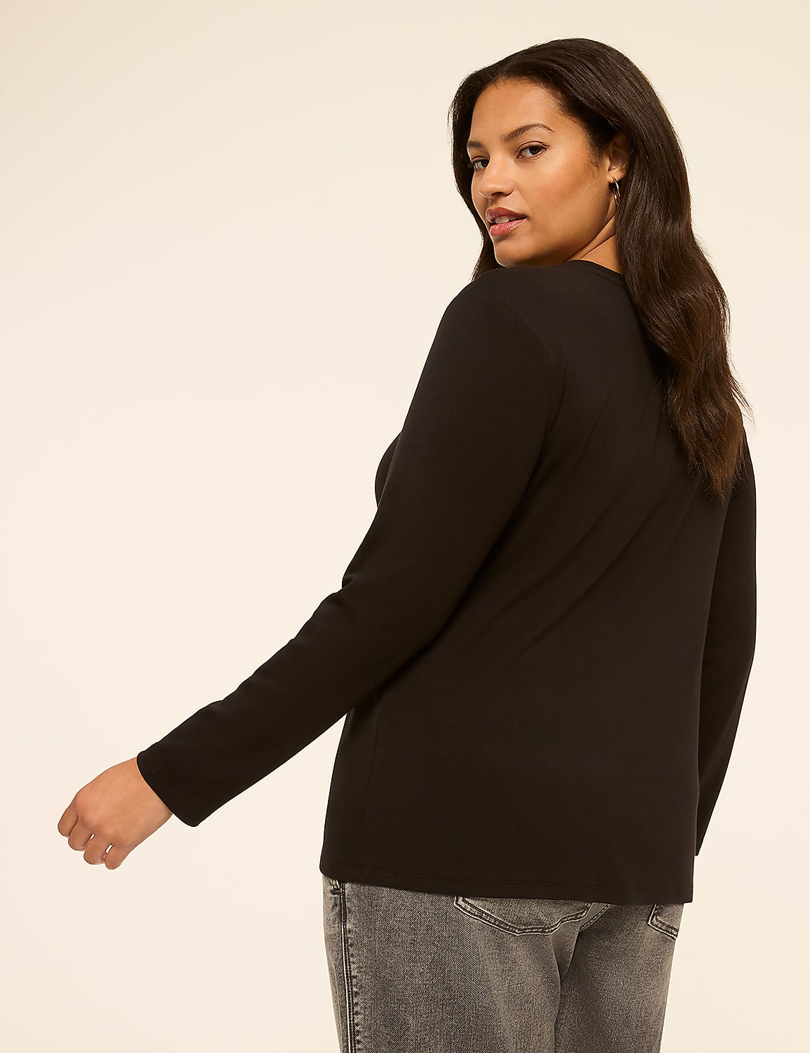 A woman in a black long-sleeved shirt and grey jeans is shown from the side against a plain, light-colored background. Product Image 2