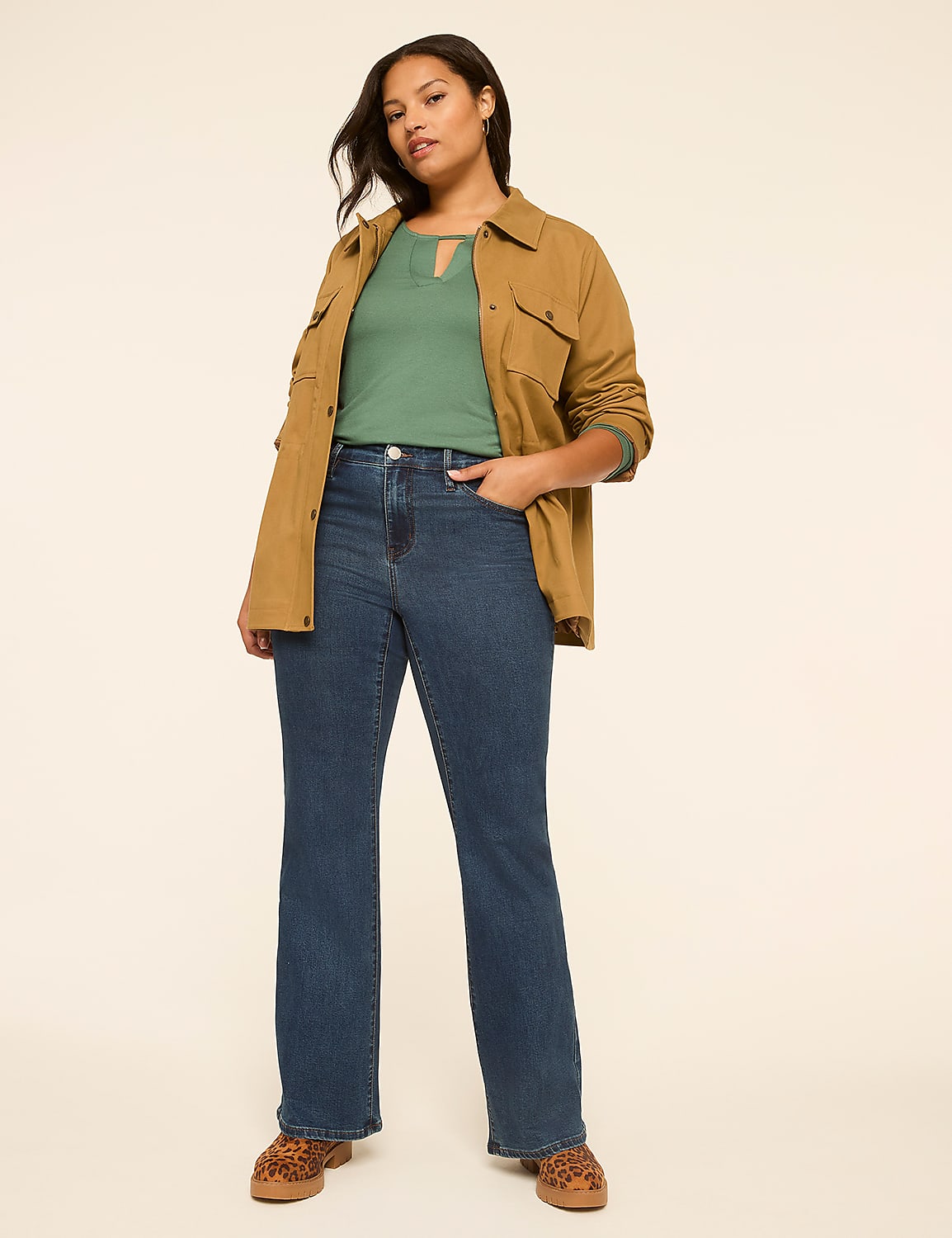 A woman in a green top, brown jacket, and flared jeans stands against a plain, light-colored background. Product Image 3