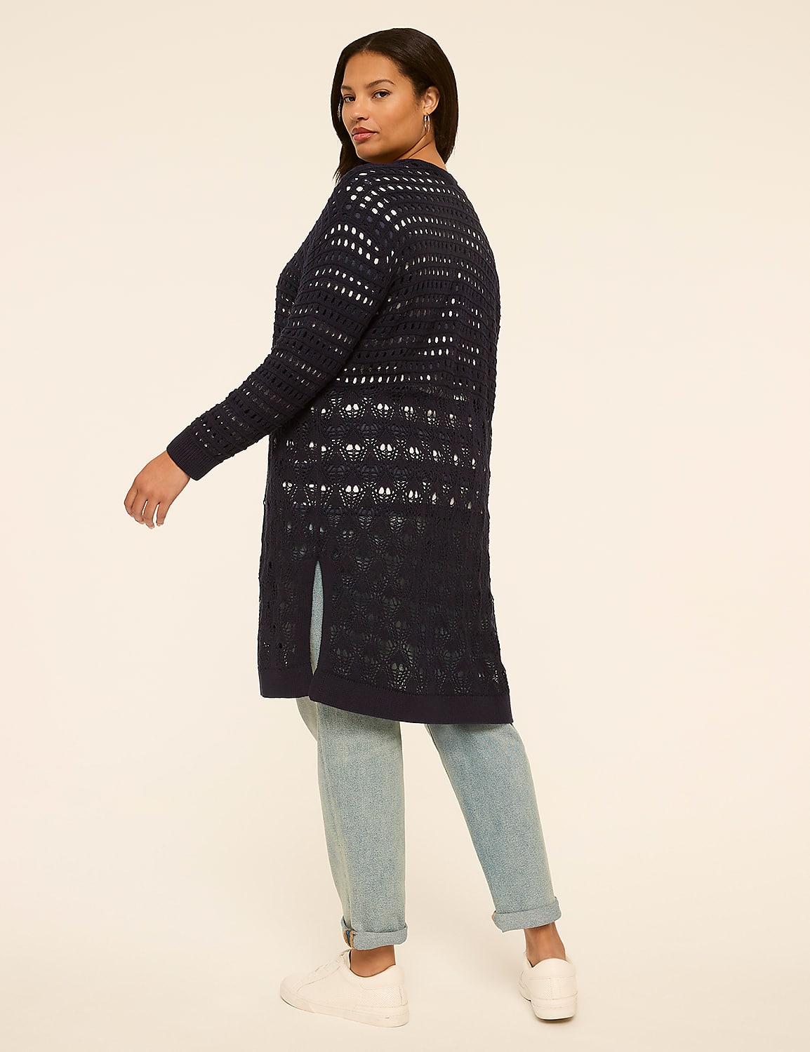 A woman in a navy crocheted cardigan and light wash jeans stands against a plain cream background. Product Image 2