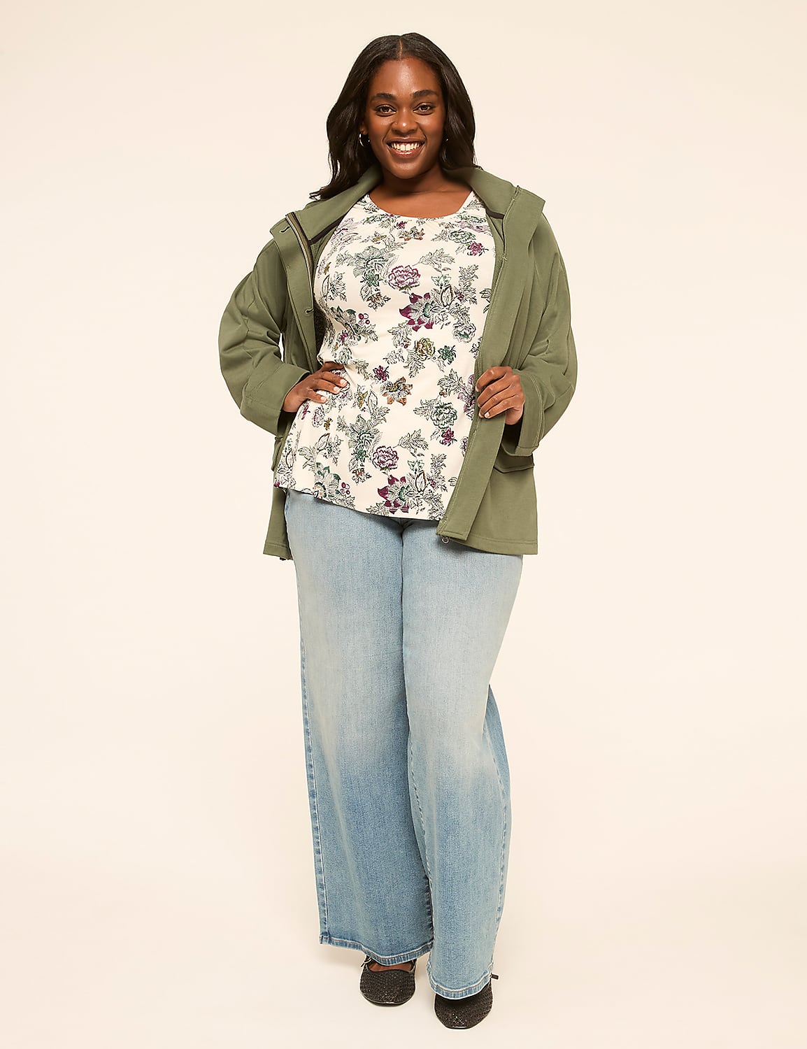 A smiling woman in a floral top, green jacket, and wide-leg jeans stands against a plain, light-colored background. Product Image 3