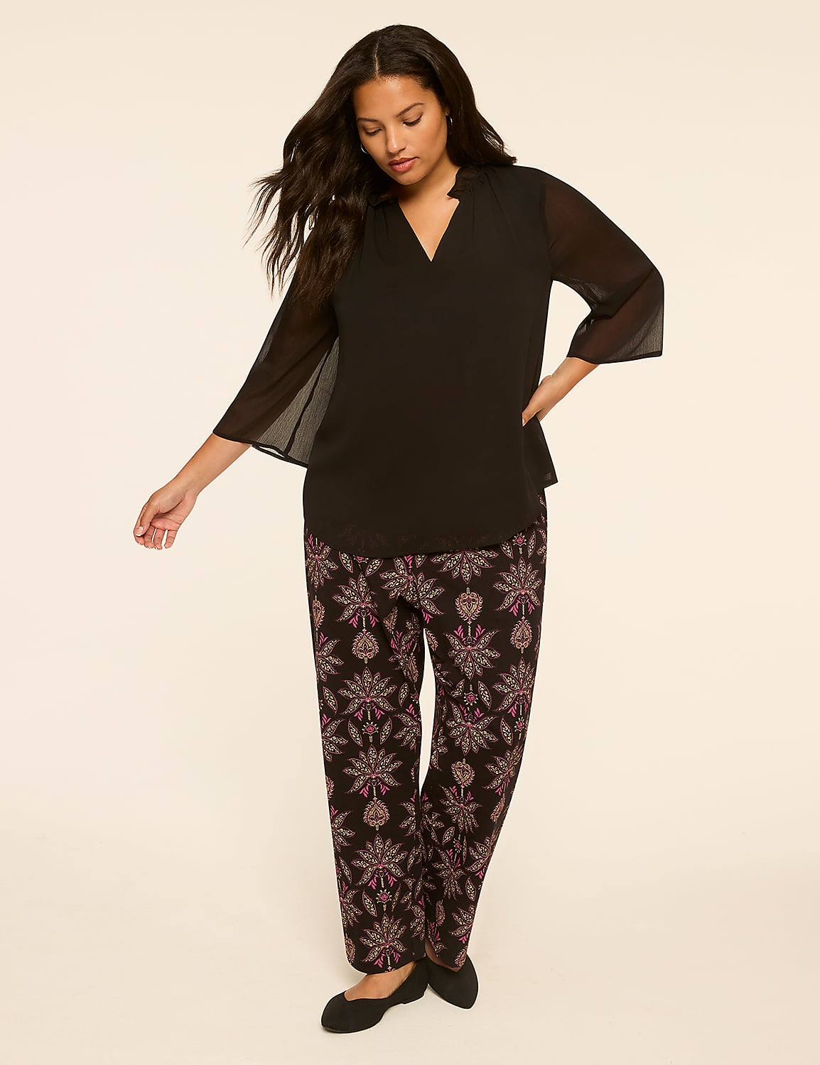 A woman in a black top and patterned pants stands against a plain, light-colored background. Product Image 3