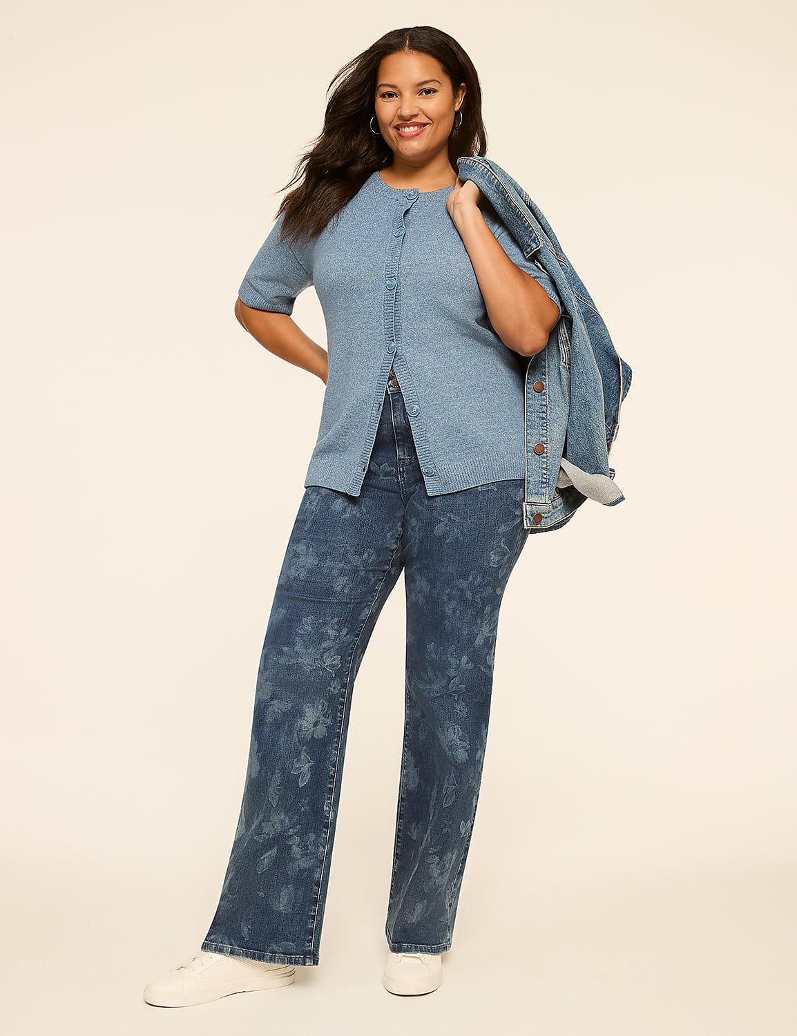 A smiling woman in a blue denim outfit stands against a plain, light-colored background, with a denim jacket draped over her shoulder. Product Image 3