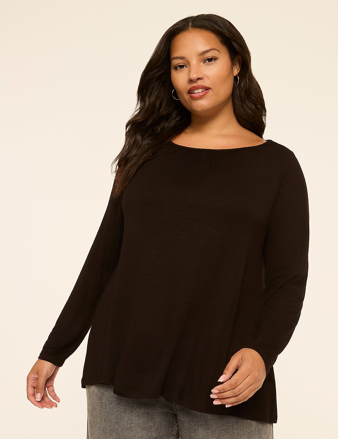 A woman in a black long-sleeved shirt and gray jeans stands against a plain, light-colored background. Product Image 1