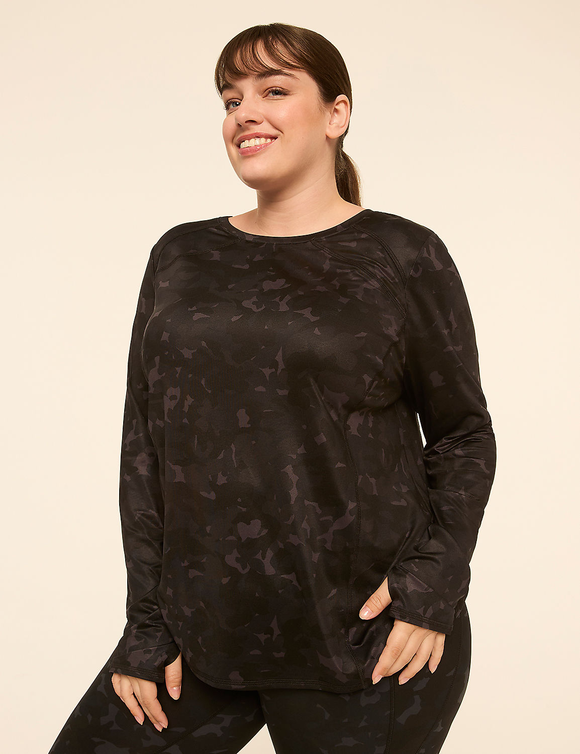 A smiling woman in a black patterned long-sleeved shirt and leggings stands against a plain, light-colored background. Product Image 1