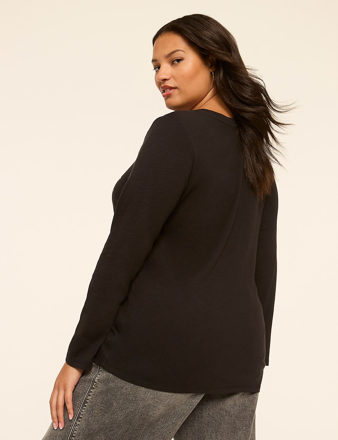 A woman in a black long-sleeved shirt and gray jeans stands against a plain, light-colored background. Product Image 2