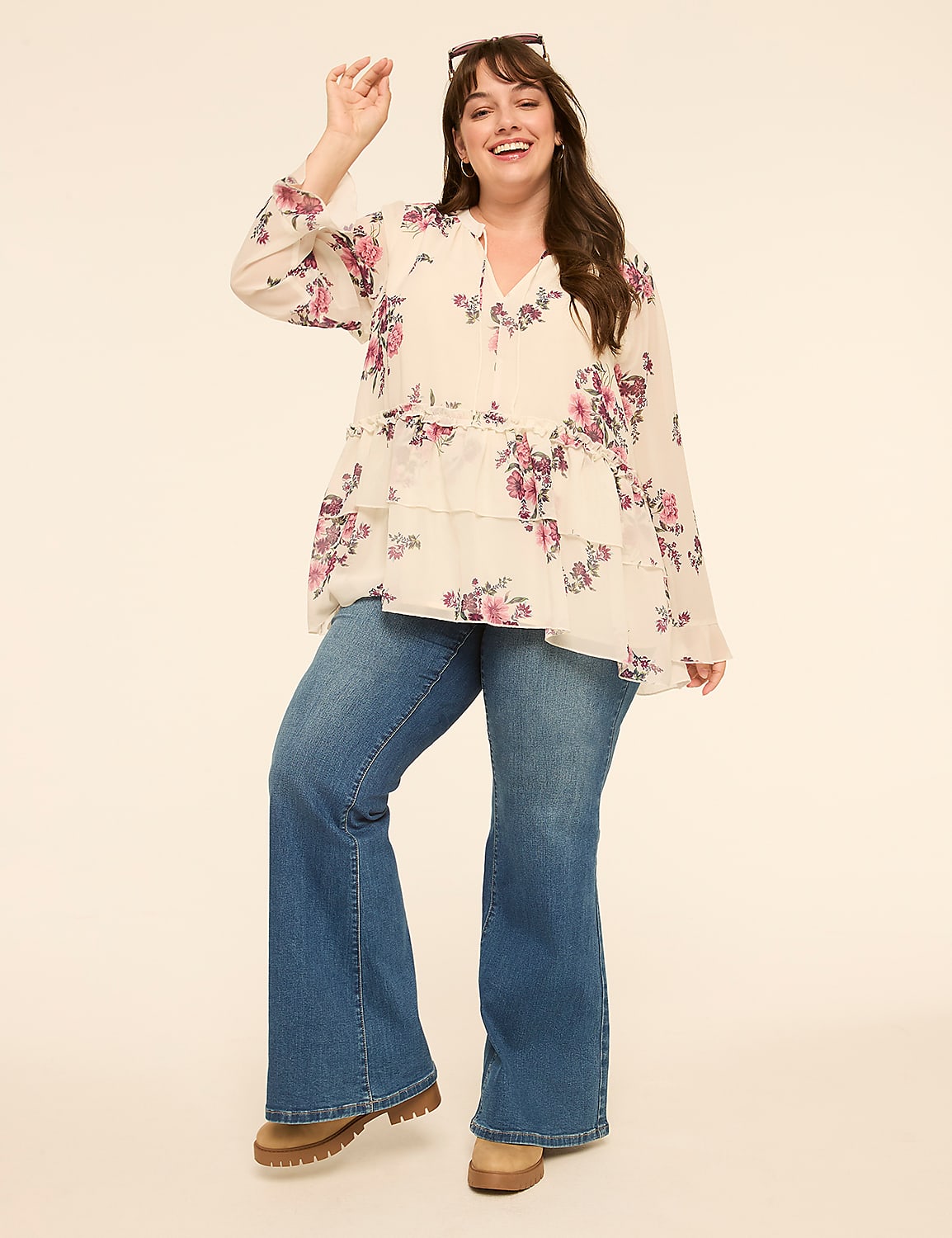 A smiling woman in a floral blouse and flared jeans poses against a plain, light-colored background. Product Image 3