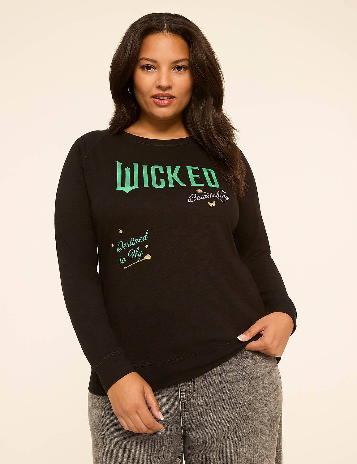 A woman in a black long-sleeved shirt with "WICKED" and "Destined to Fly" printed on it stands against a plain, light-colored background. Product Image 1