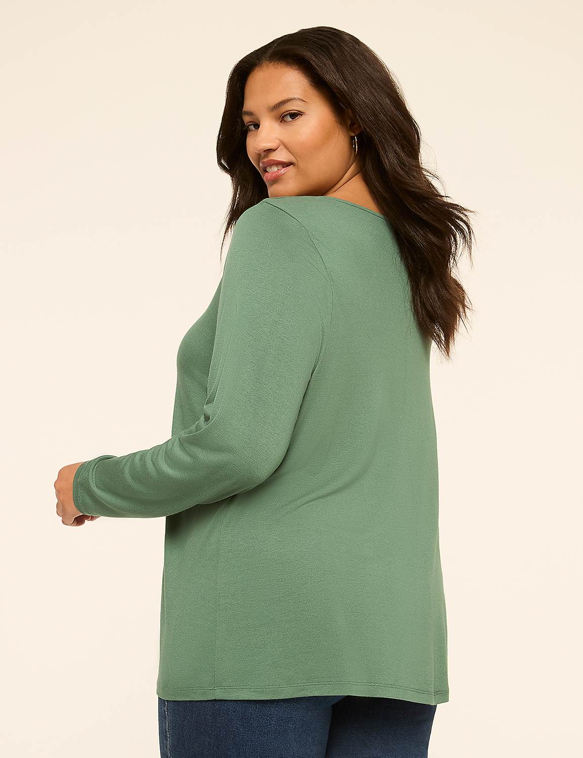 A woman in a green long-sleeved shirt and blue jeans poses against a plain, light-colored background. Product Image 2
