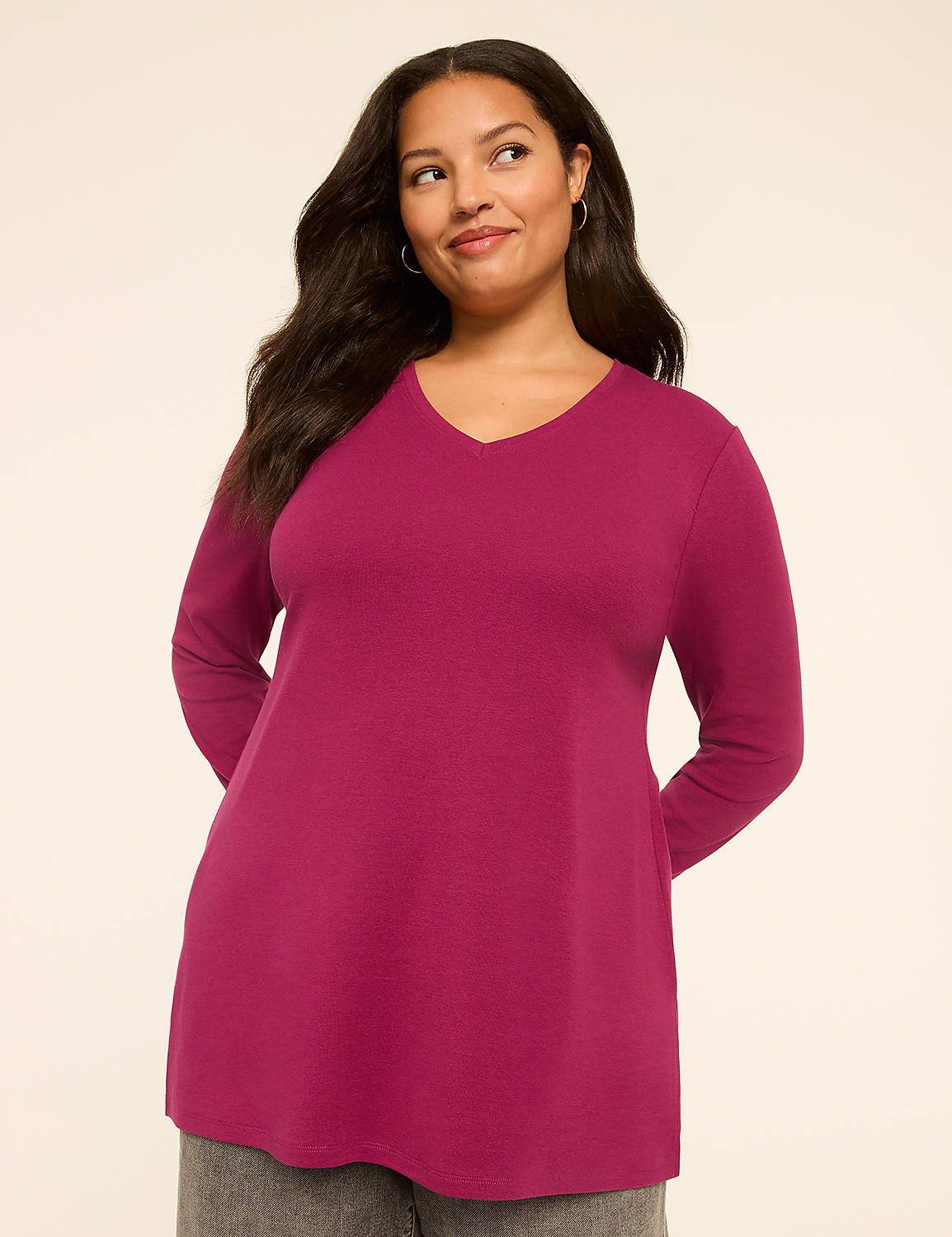 A woman in a magenta v-neck shirt stands against a plain, light-colored background. Product Image 1