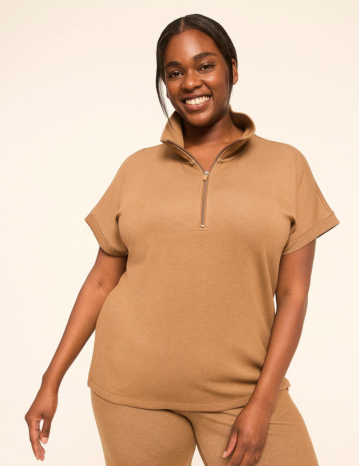 A smiling woman in a brown quarter-zip top and matching pants stands against a plain, light-colored background. Product Image 1